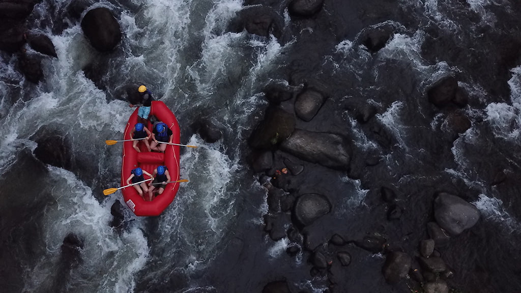 Dramatic shot of whitewater rafters traversing a rocky river